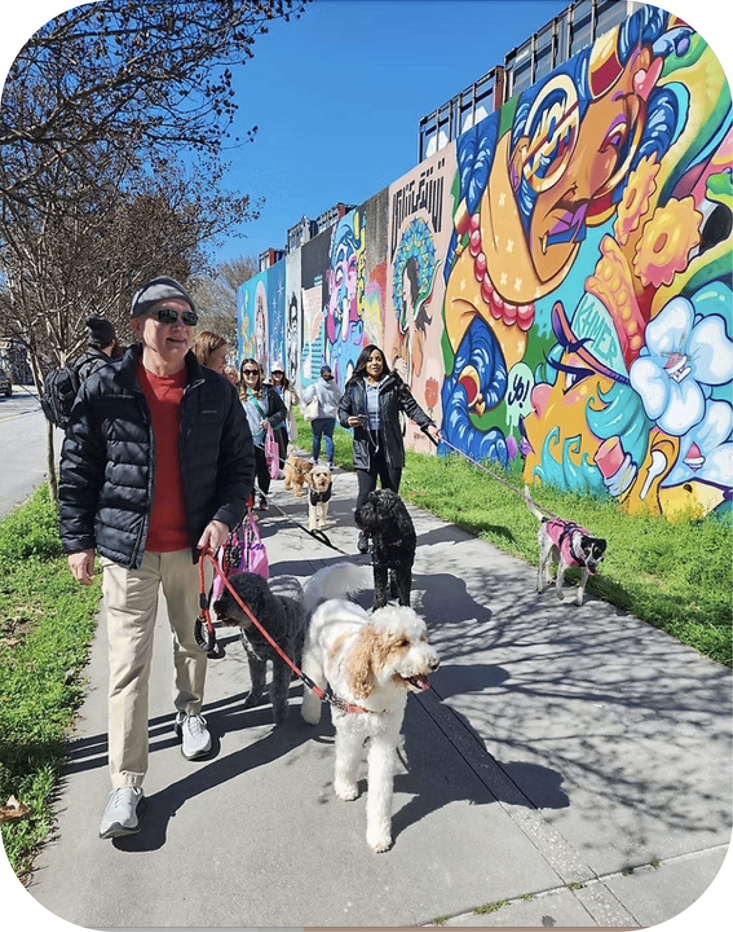 Group walking dogs along a BeltLine mural